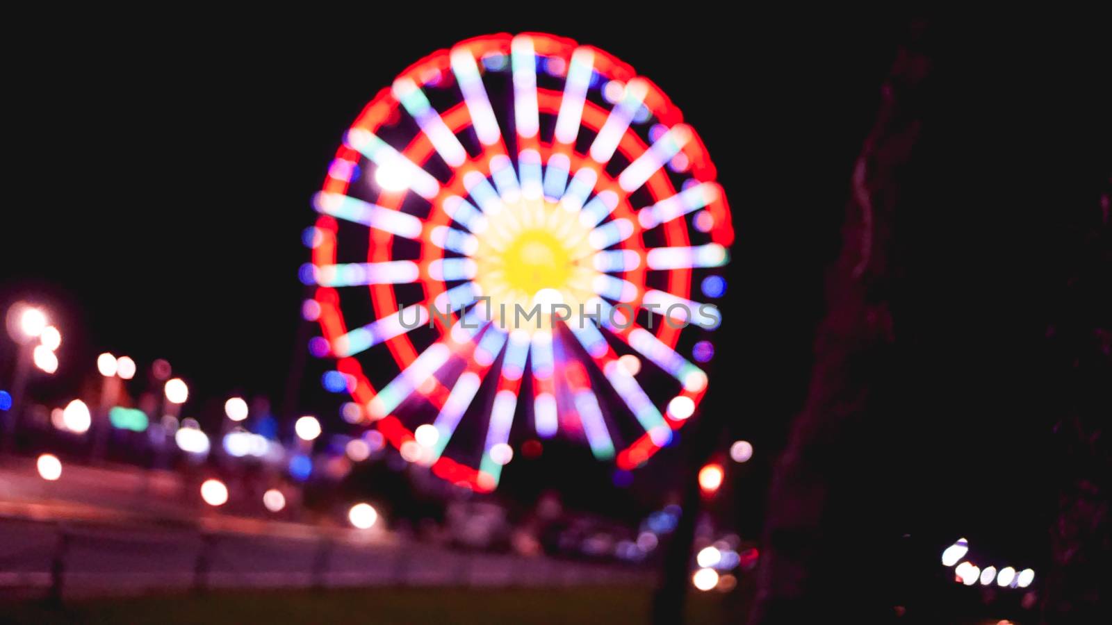 Out of focus abstract of ferris wheel and empty road at night by natali_brill