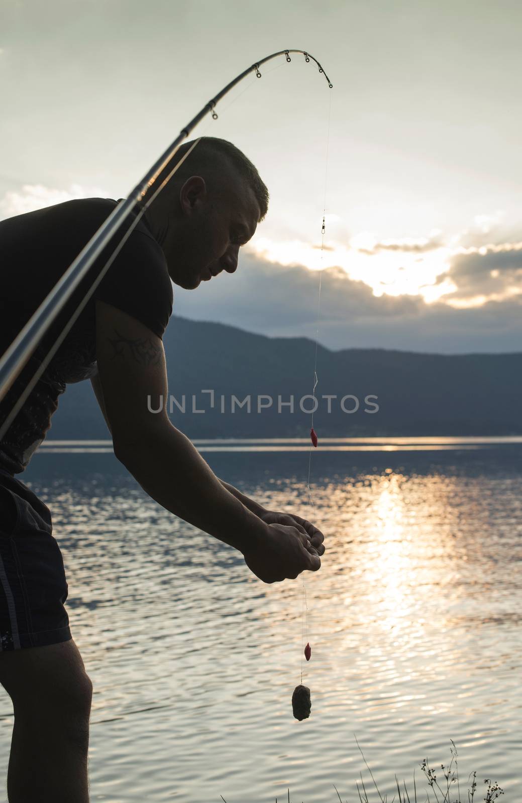 Man on fishing with rod. Mountain lake