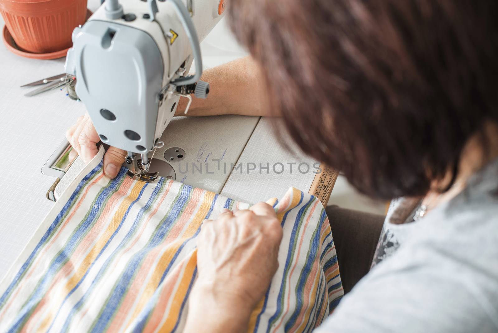Women sew on sewing machine. White machine