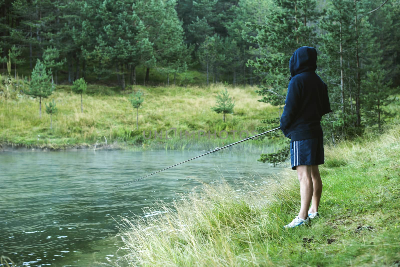 Man with fishhook in front of mountain dam