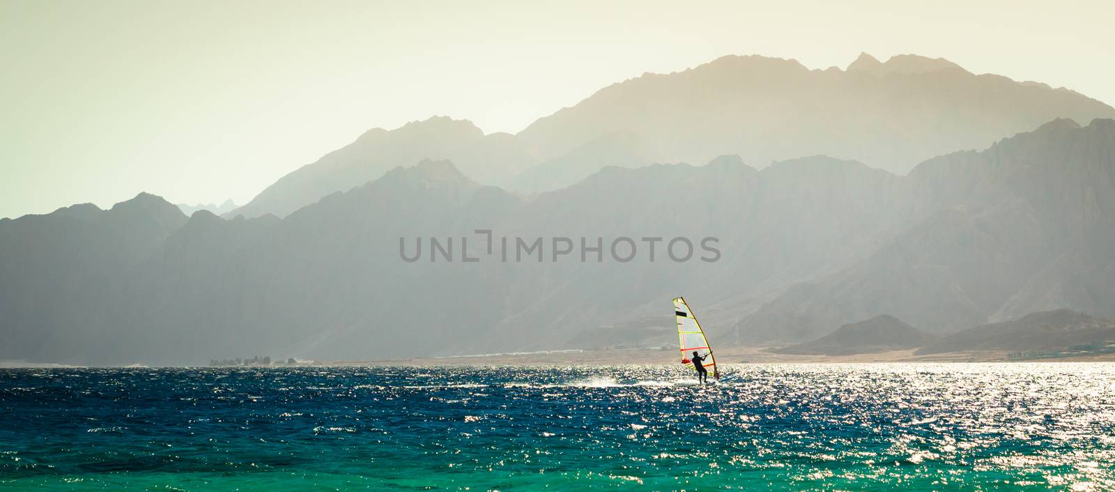 surfer rides in the Red Sea against the backdrop of a rocky coast in Egypt in the evening