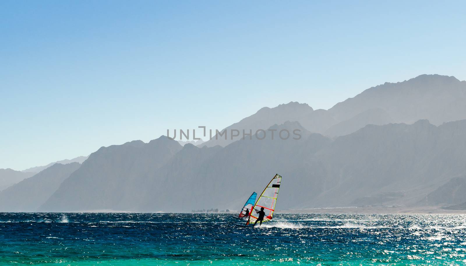 two windsurfers ride on the background of high rocky mountains in Egypt Dahab
