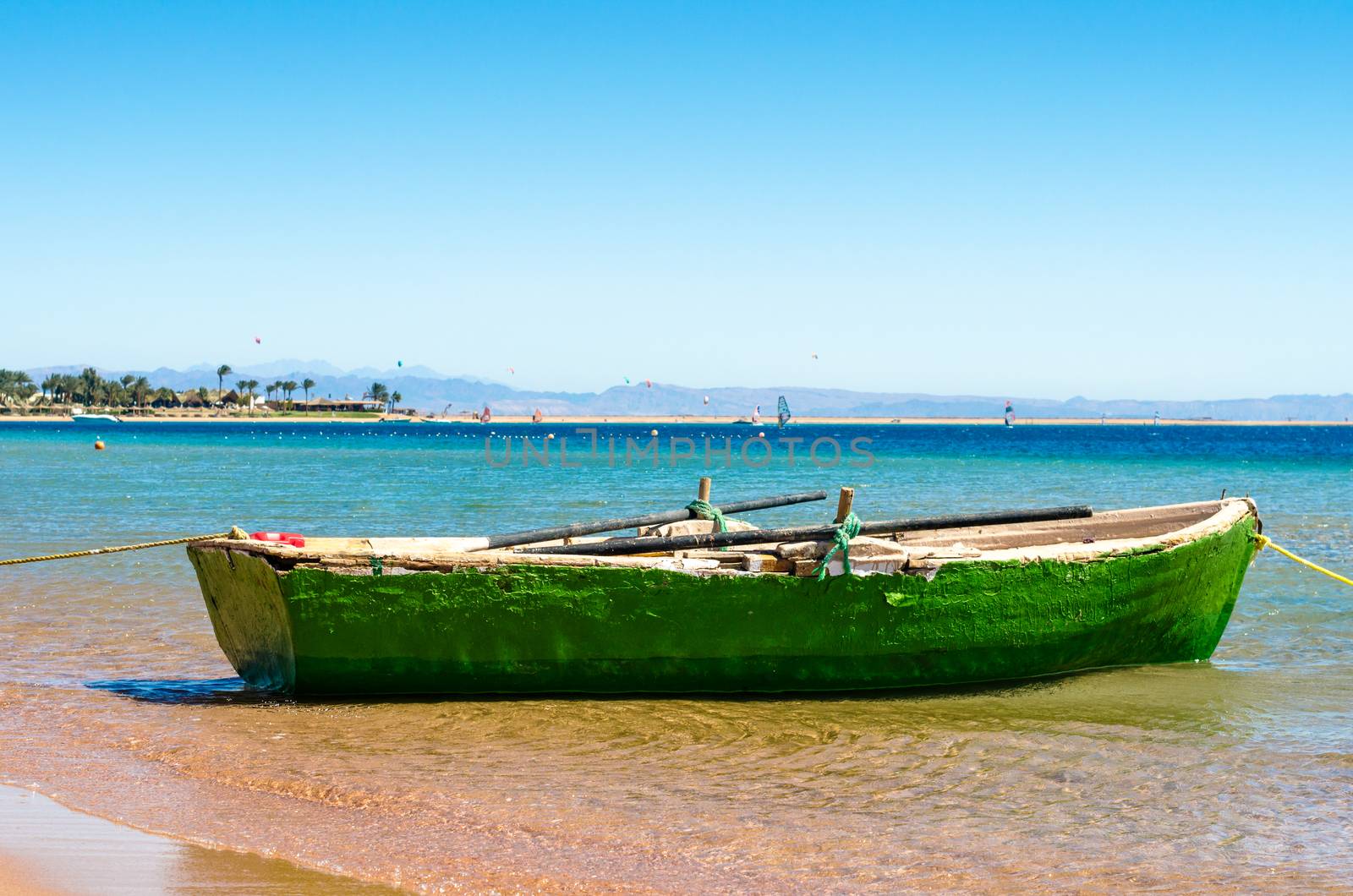 Old wooden fishing boat in the sea on the background of the beach with palm trees in Egypt. Dahab