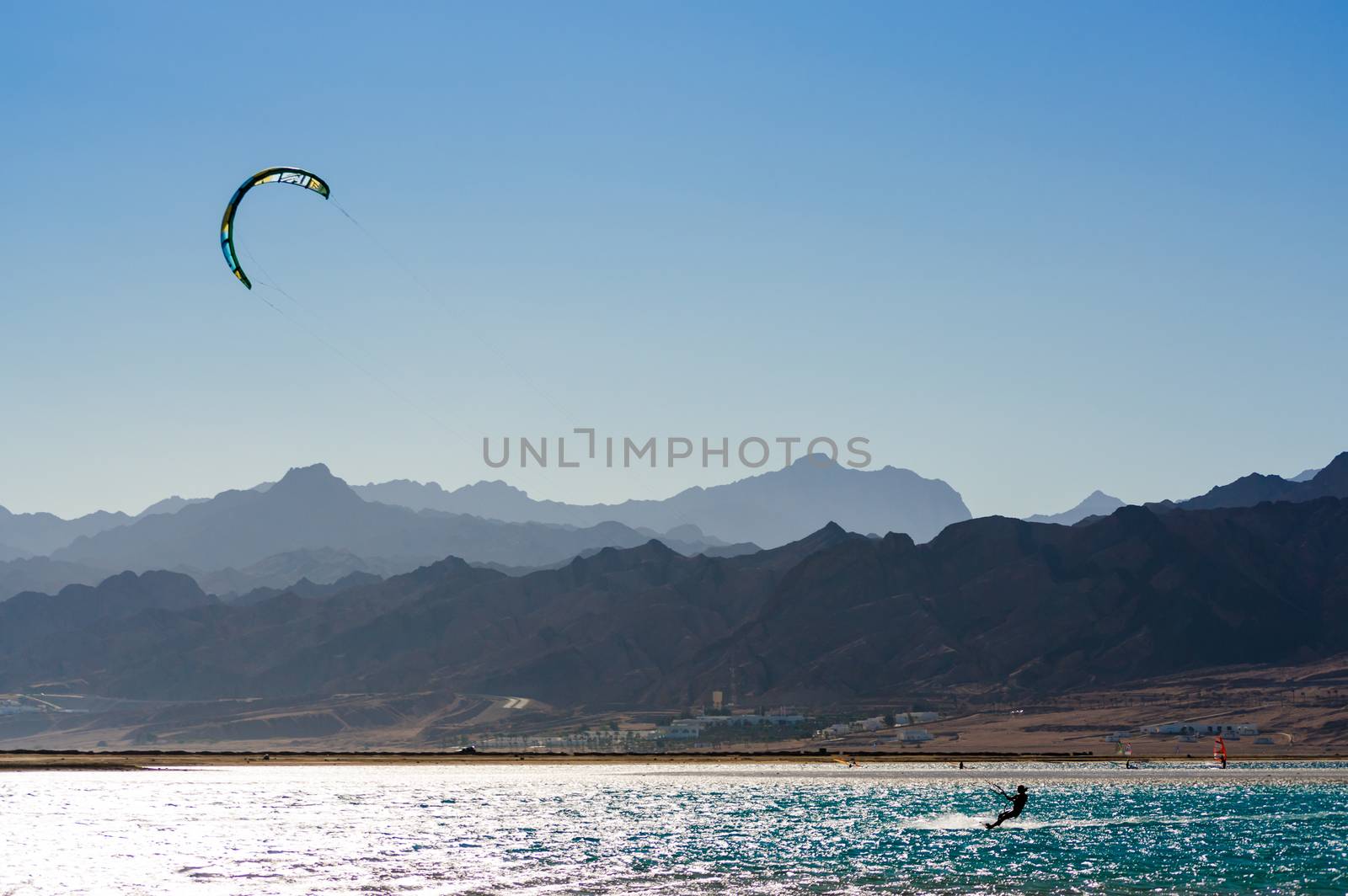 kitesurfer rides in the Red Sea on the background of a rocky coast in Egypt Dahab