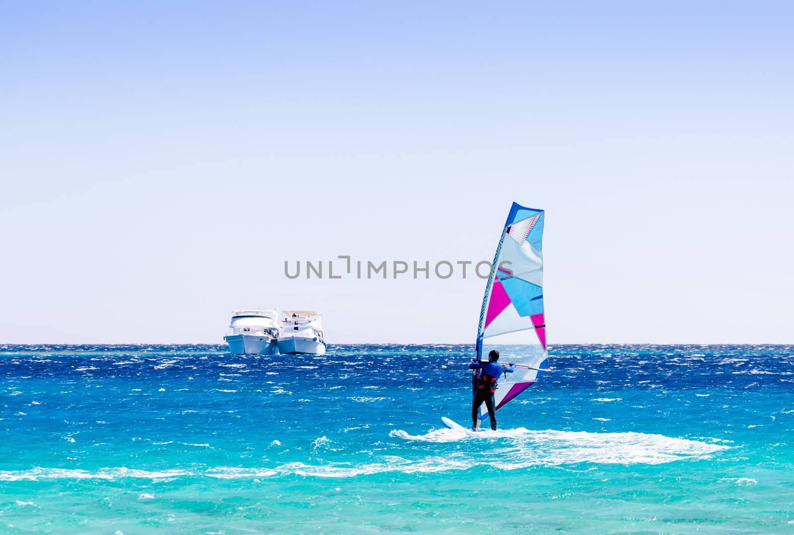 surfer rides in the Red Sea against the backdrop of two ships in Egypt Dahab