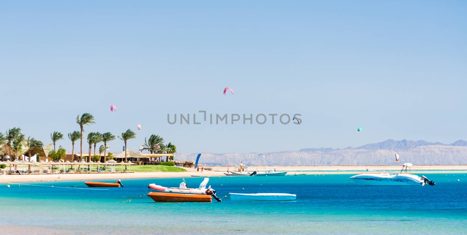 hotel with palm trees on the Red Sea in Egypt with boats and kite surfers