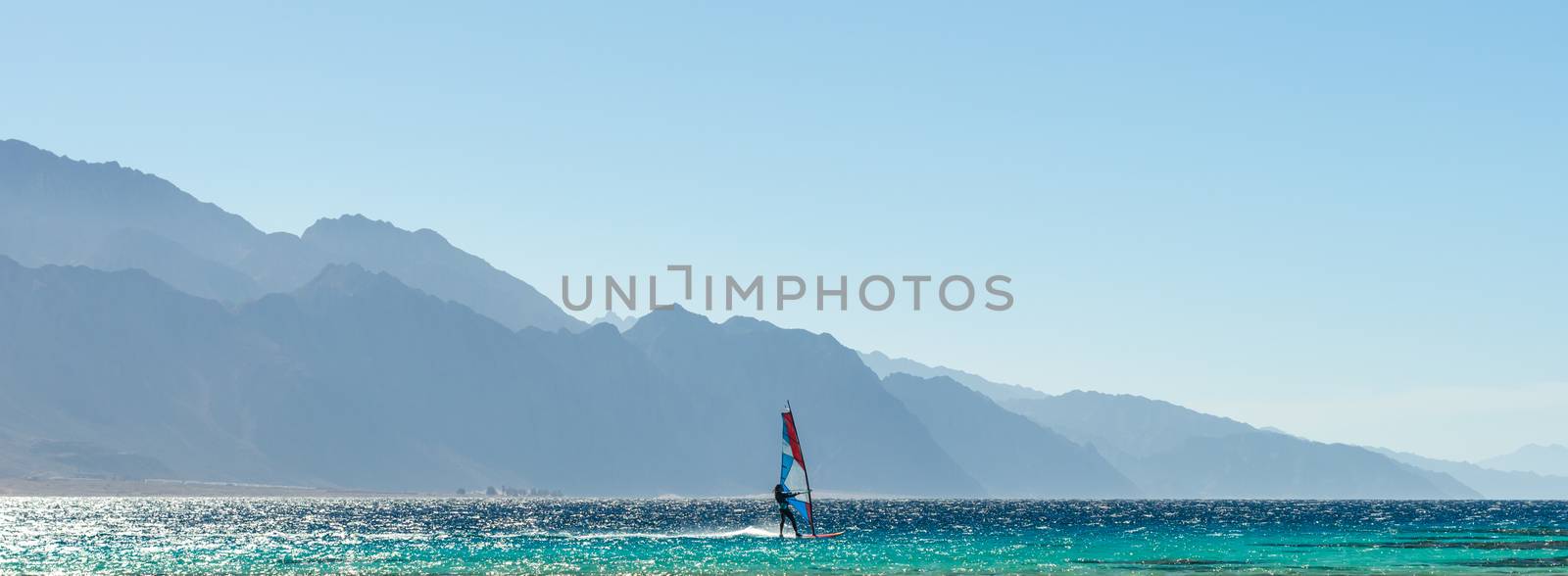 windsurfer rides in the Red Sea against the backdrop of high rocky mountains in Egypt