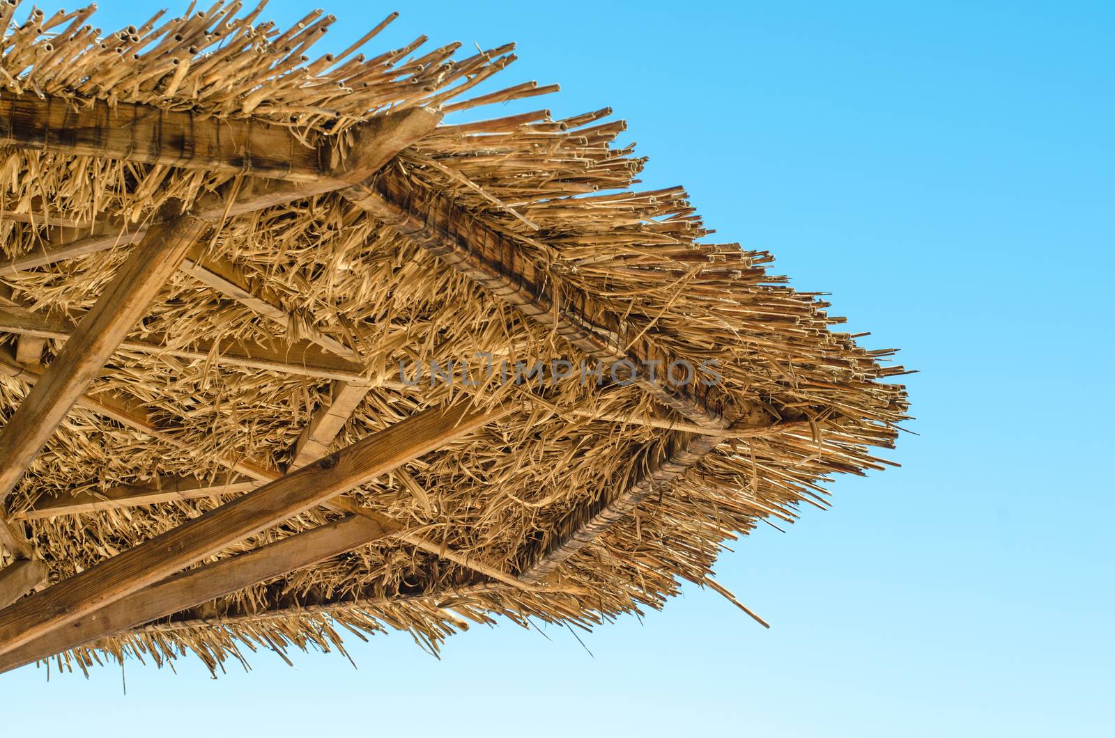 fragment of a cane beach umbrella close up against a blue sky