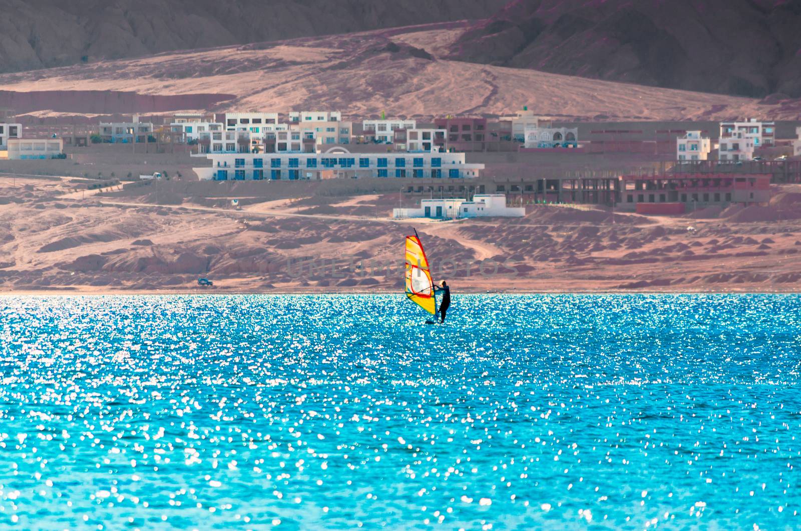 one surfer with a sail on a rocky shore and hotels in the Red Sea in Egypt