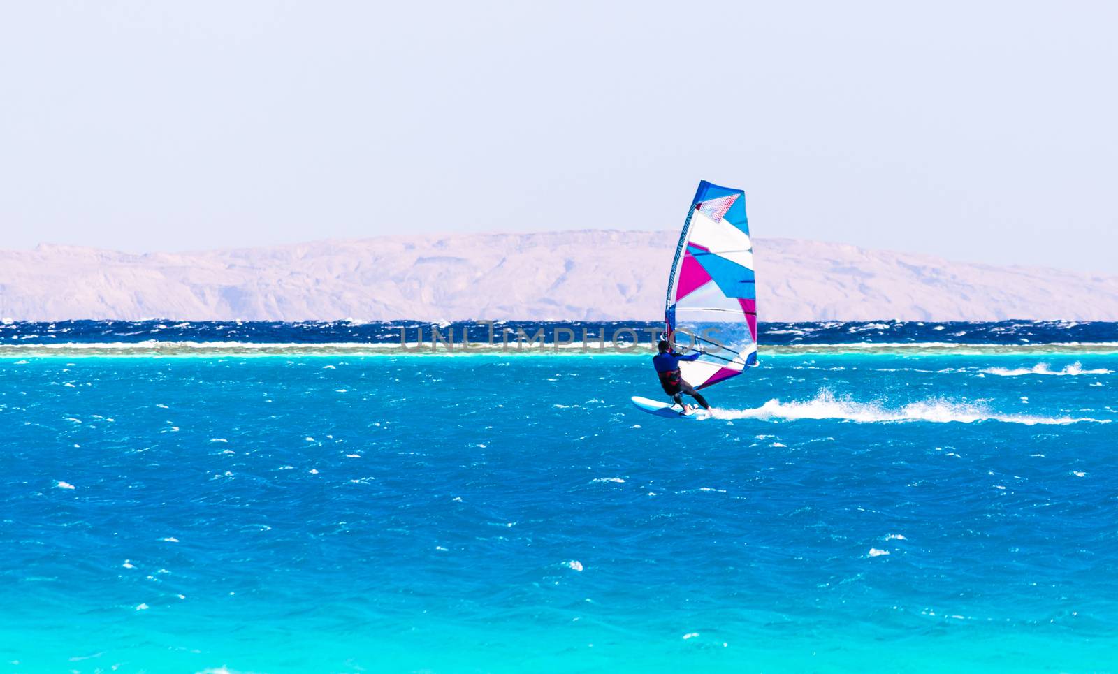 surfer rides in the Red Sea on the background of the rocky coast in Egypt Dahab