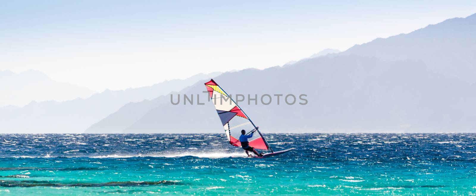surfer rides in the Red Sea on the background of the rocky coast in Egypt Dahab