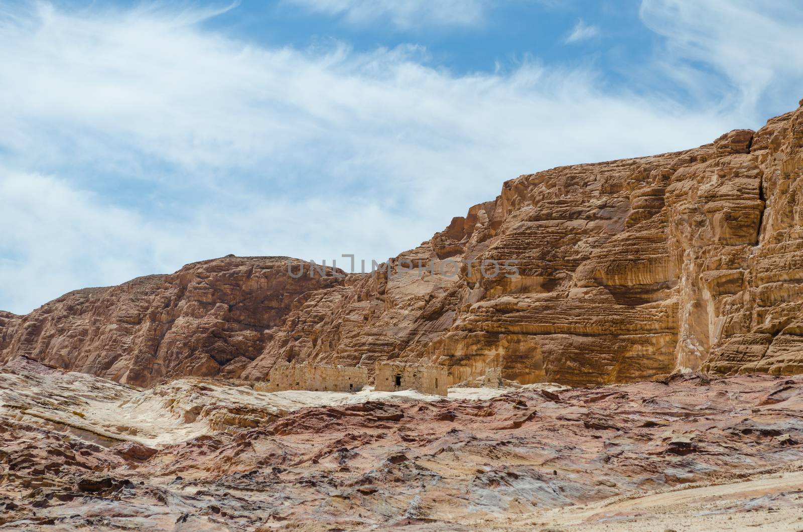 ruins of houses in the desert against the backdrop of high rocky mountains and blue sky with white clouds in Egypt Dahab South