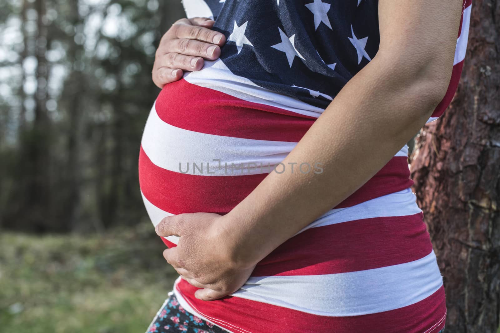 Pregnant woman in the forest. American national flag shirt