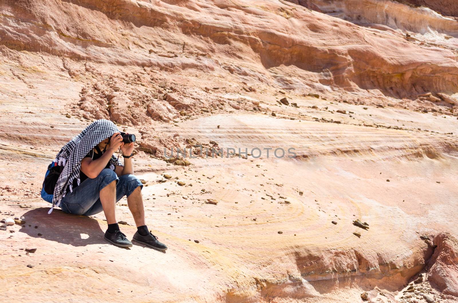 photographer takes pictures sitting on a rock in Egypt Dahab