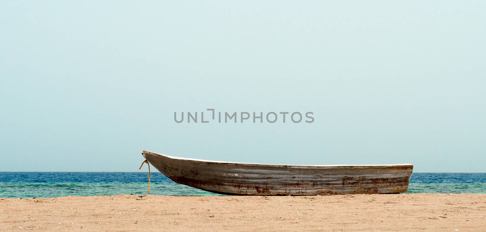 old boat in the sand against the background of the sea and the horizon