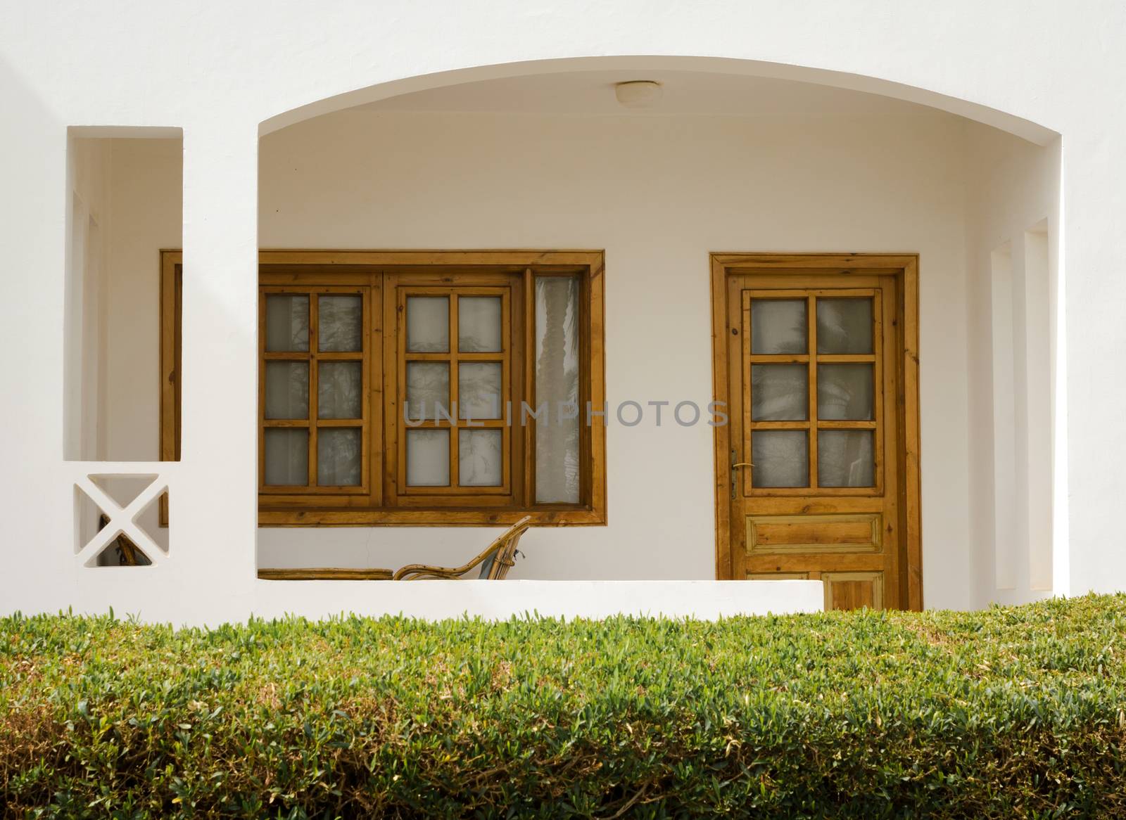 white holiday house with a bush with green leaves nearby