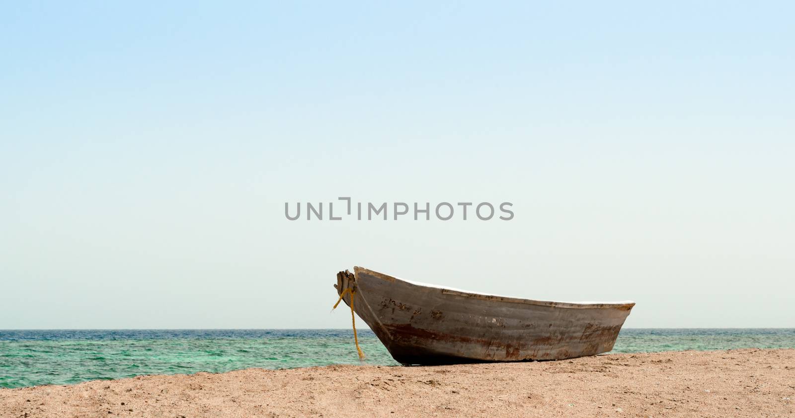 old boat in the sand against the background of the sea and the horizon