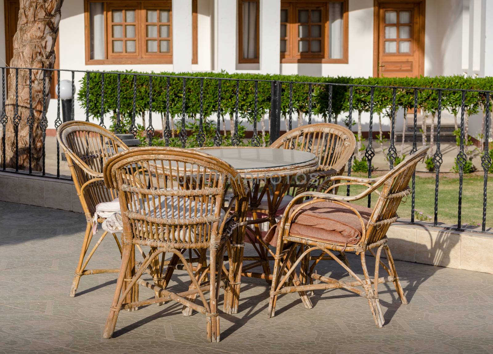 wooden rotan chairs and a round table on the background of the resort house