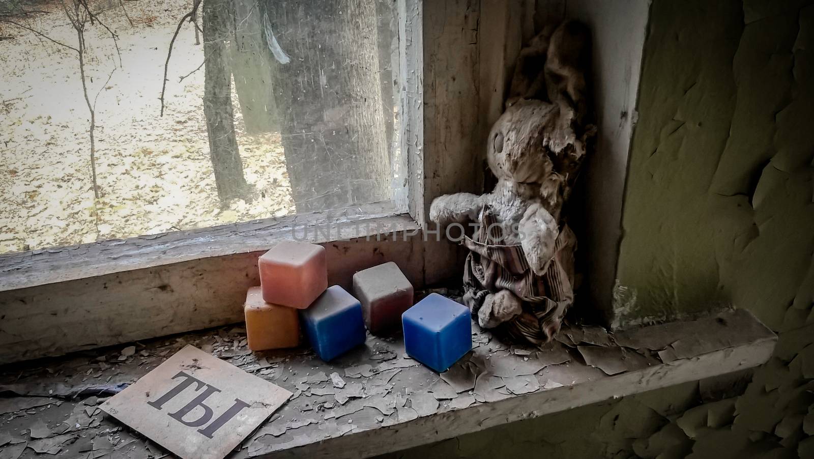 russian word you on paper next to an old doll and colored dusty cubes on a windowsill in an abandoned house in Chernobyl
