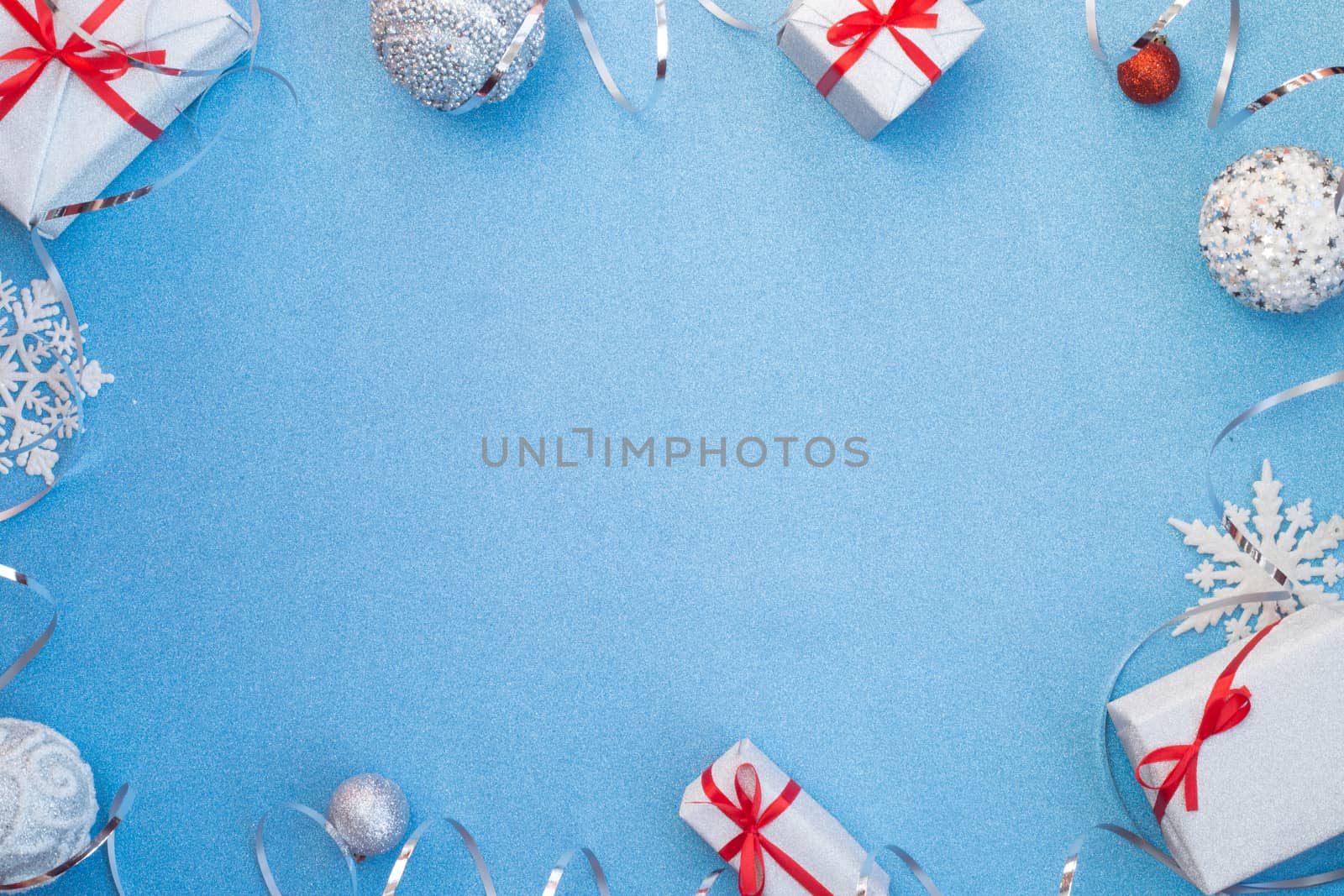 Blue glitter texture christmas background and silver gifts with red ribbon bow baubles snowflakes and ribbons , copy space for text , top view flat lay template