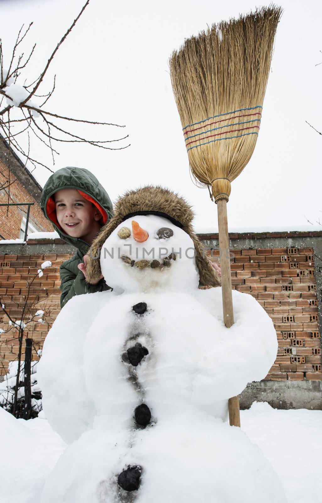 Snowman and child in the yard. Winter