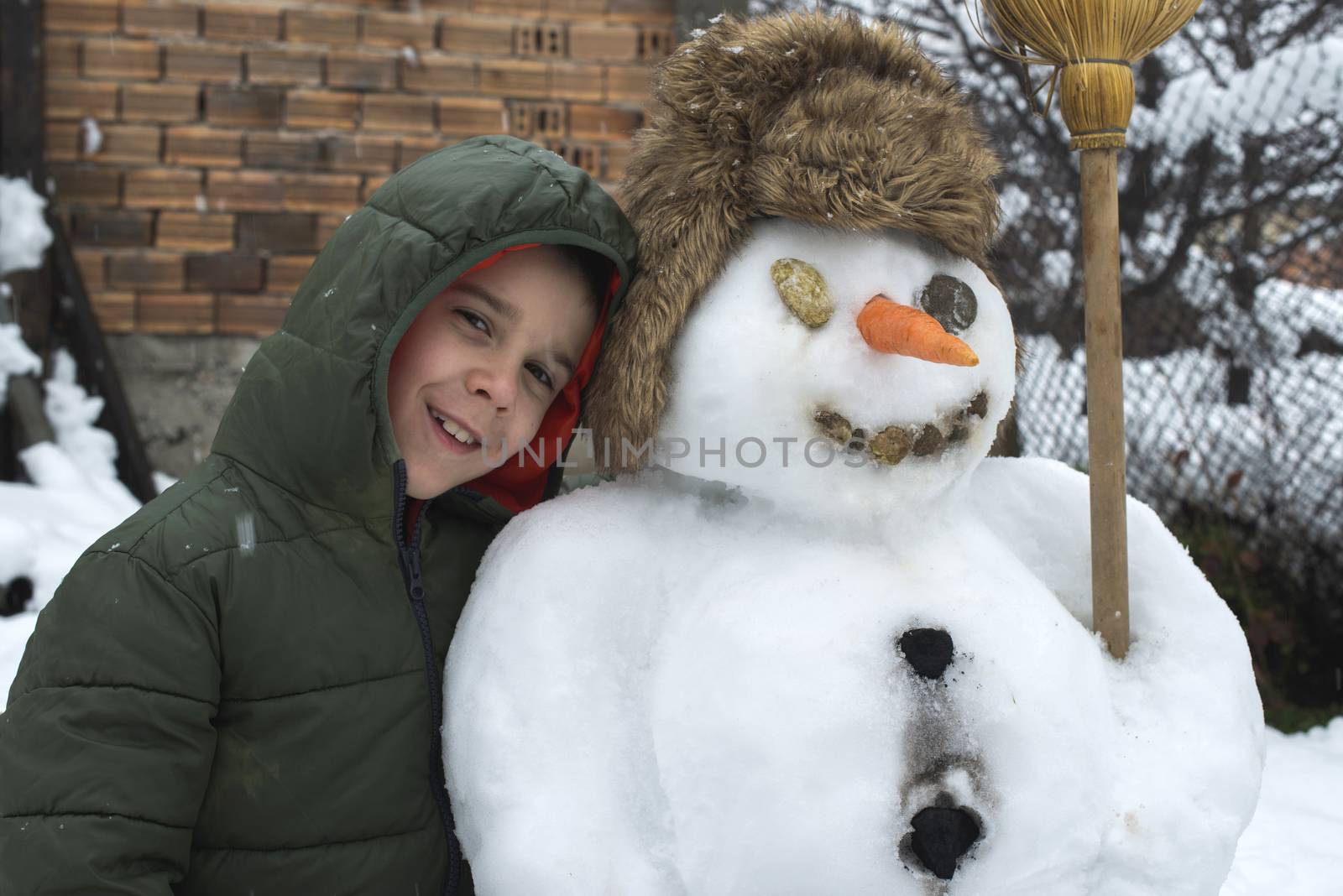 Snowman and child in the yard by deyan_georgiev