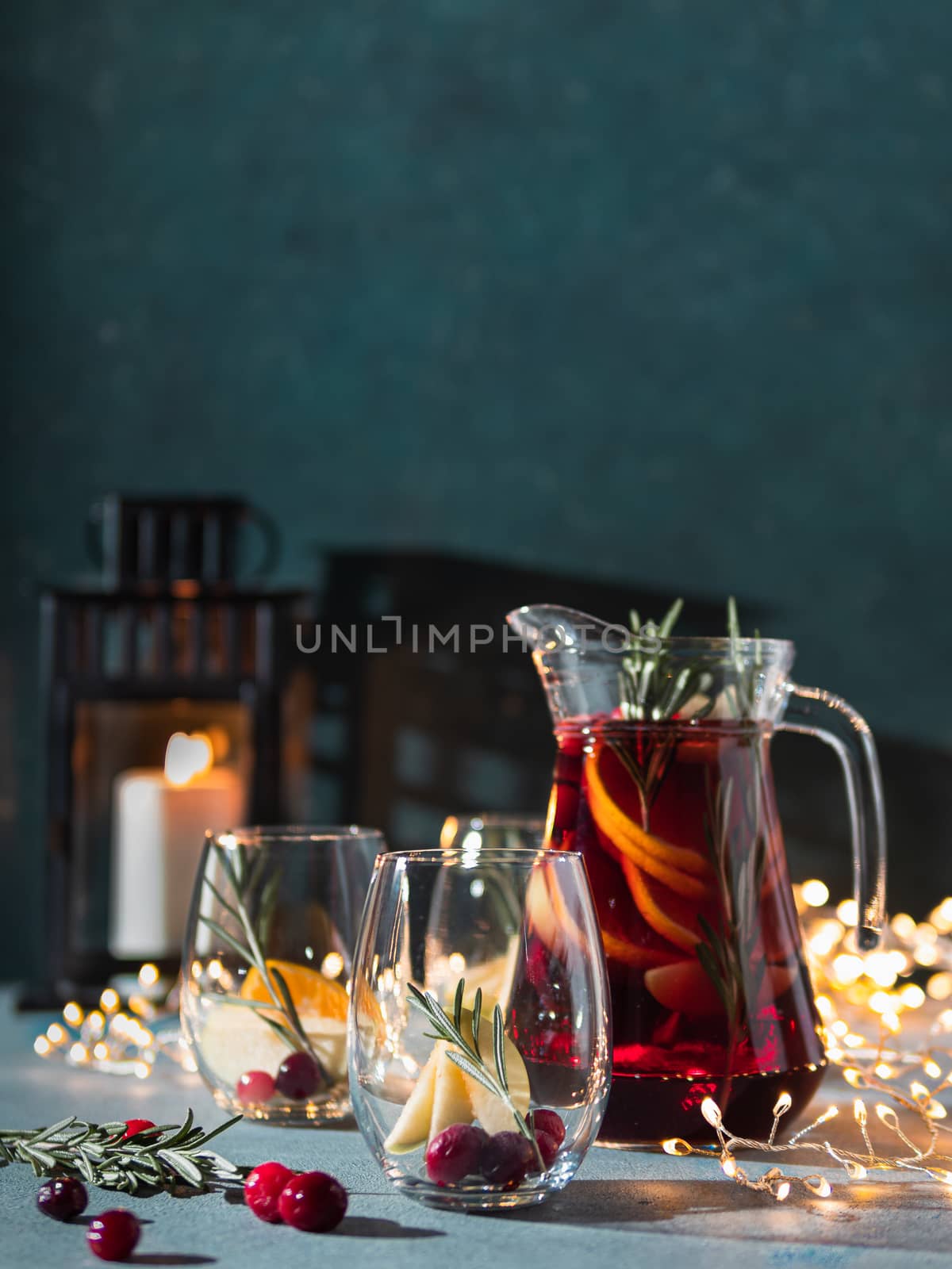 Winter sangria on dark christmas holiday background. Jugful of sangria and glasses with fruit slice, cranberry and rosemary. Copy space for text or design. Vertical.