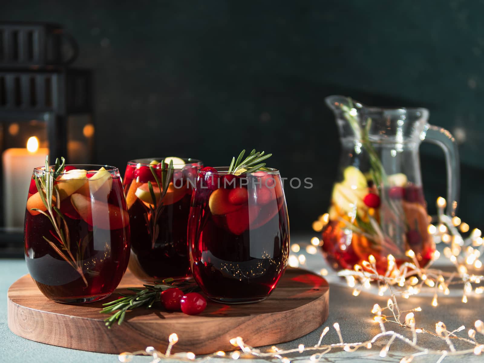 Winter sangria on dark christmas holiday background. Jugful of sangria and glasses with fruit slice, cranberry and rosemary. Copy space for text or design. Horizontal.