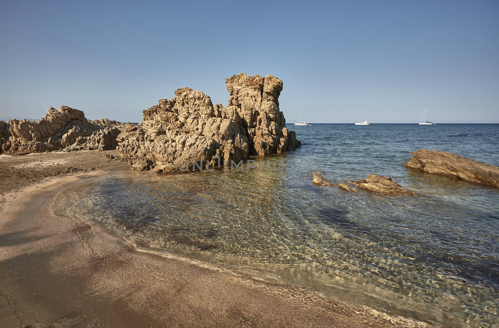 South rocky sardinia beach with waves of transparent sea coming ashore to merge with golden beach.