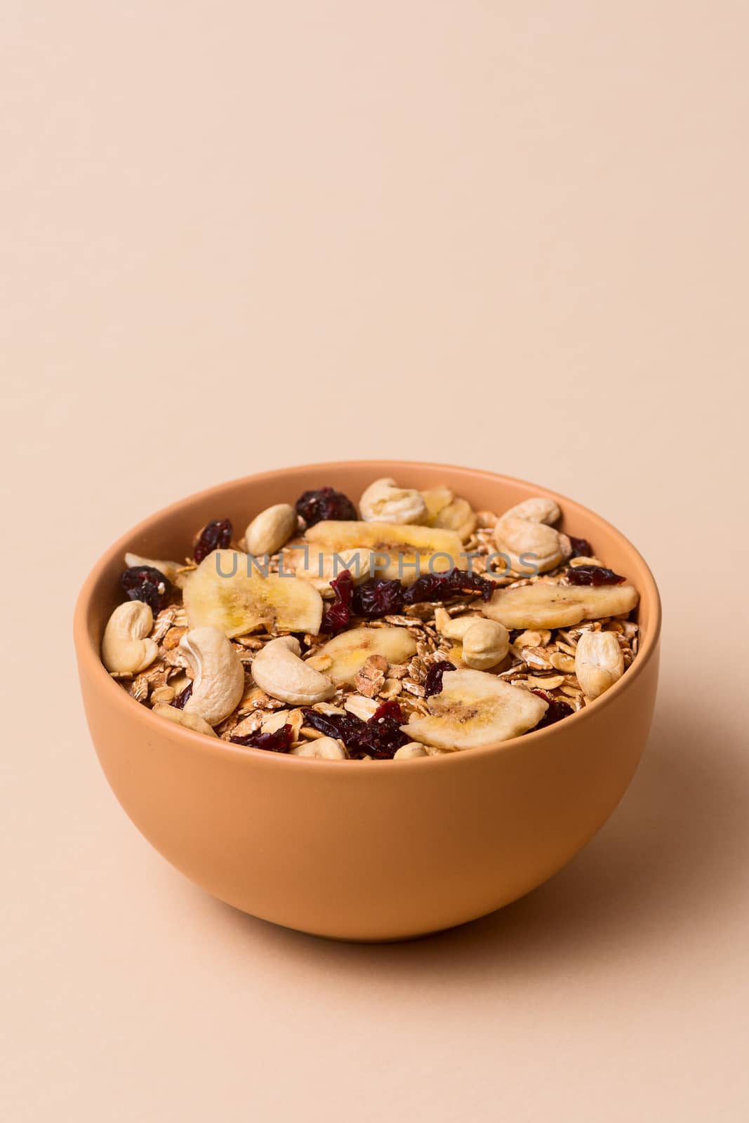 A fresh granola with dried and candied nuts and fruits in beige  by alexsdriver