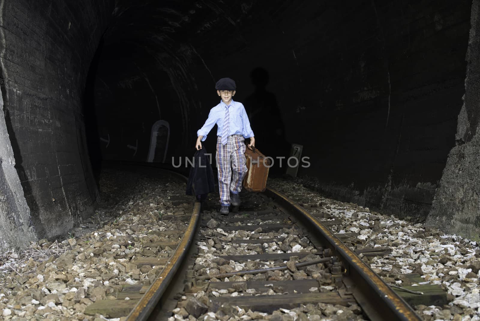 Child walking on railway road with vintage siutcase.
