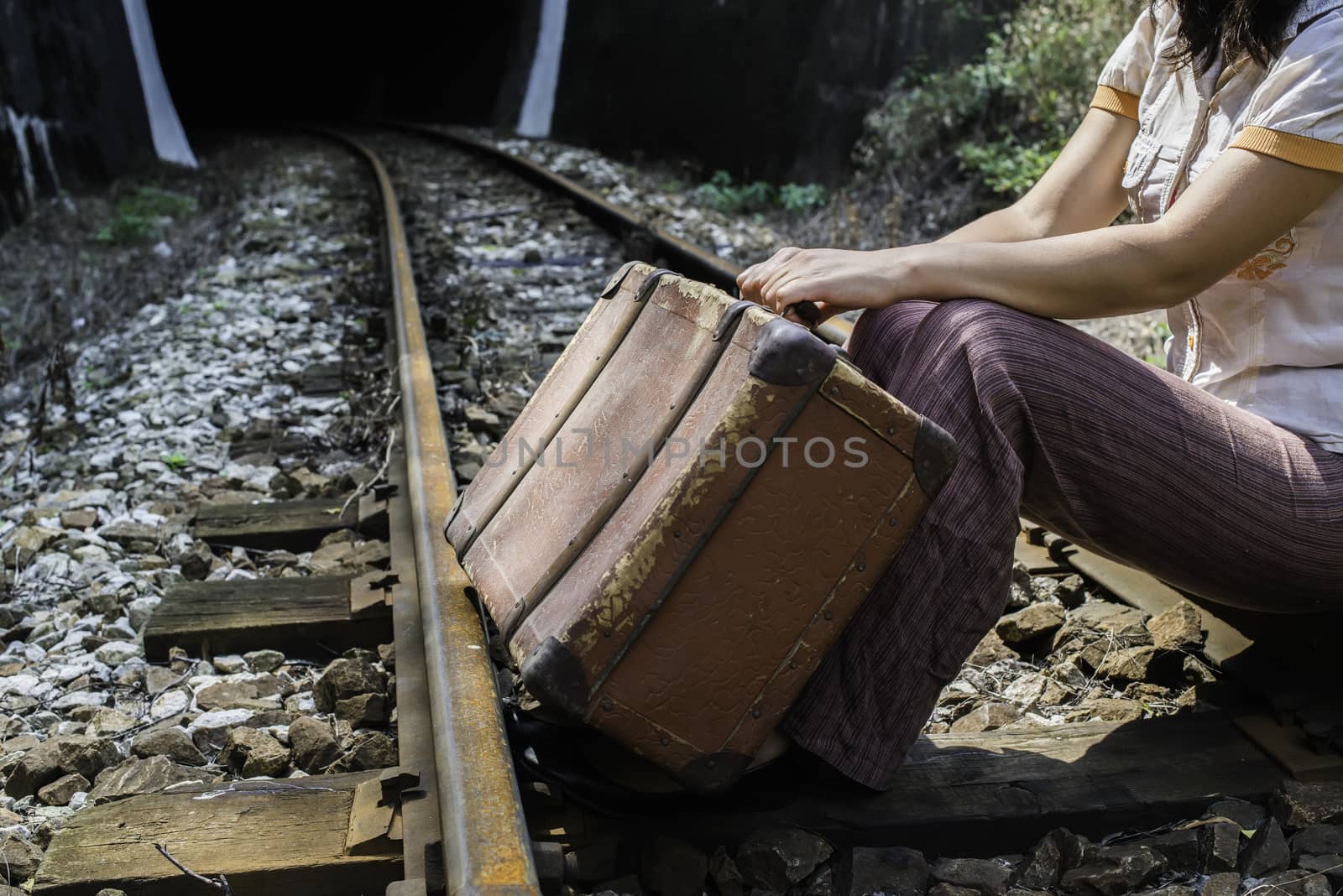 Woman and vintage suitcase on railway road and tunnel. 