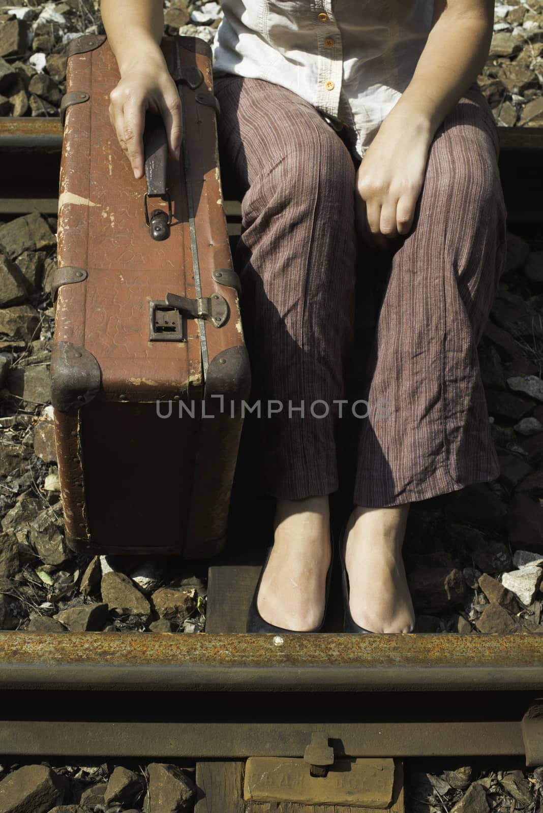 Woman and vintage suitcase on railway road. 