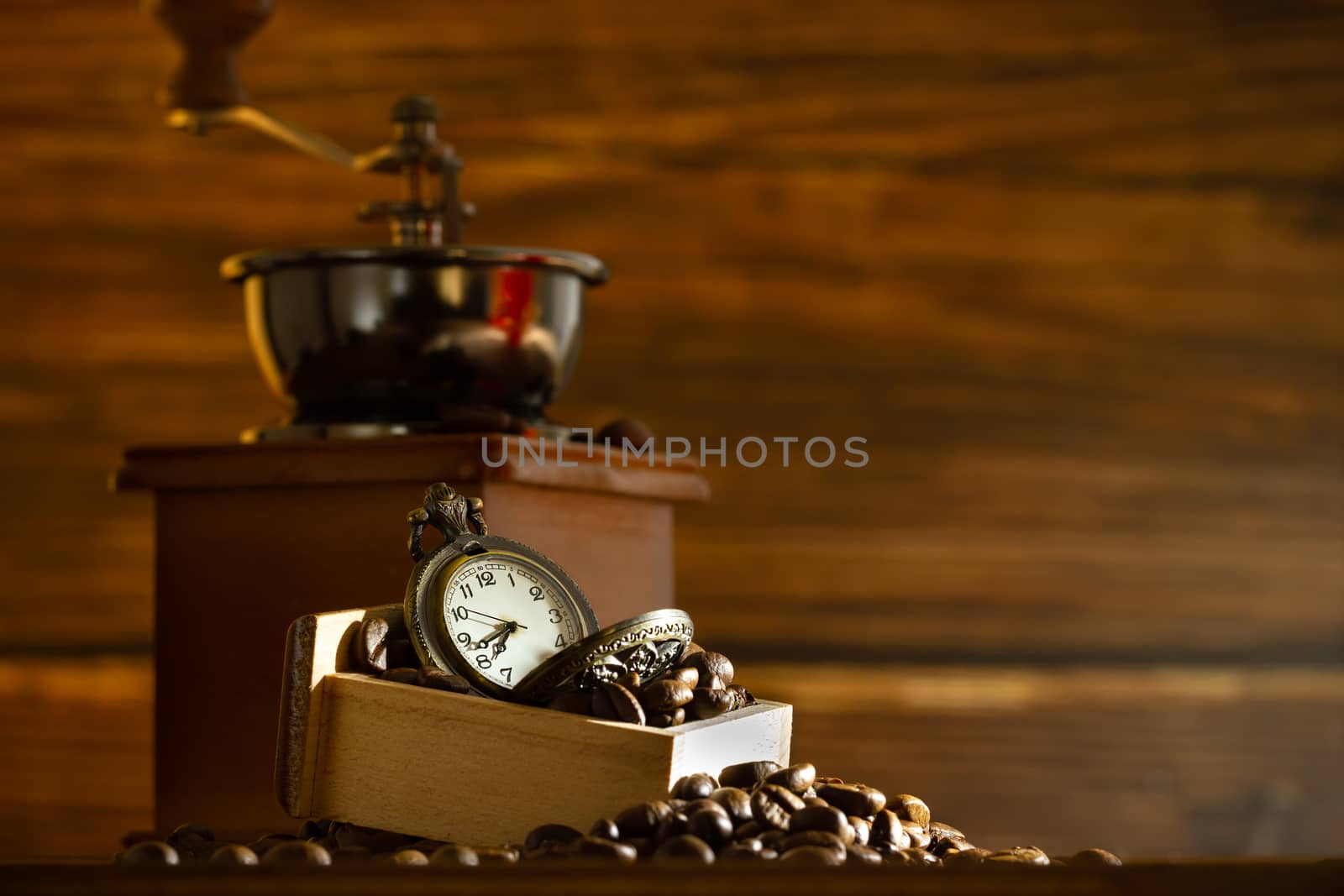 Coffee bean and pocket watch. Manual grinder on table in morning. Concept of coffee time.