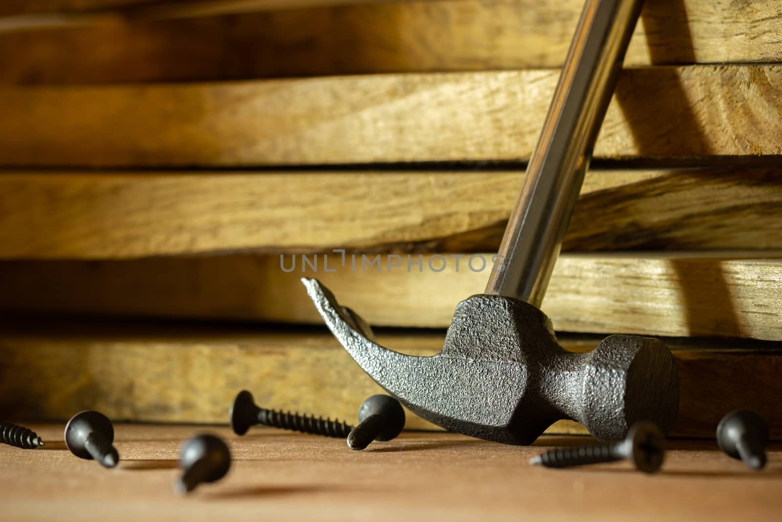 Hammer and screw on lumber in lighting and shadow of the sunshine in morning. The concept of woodcraft or carpentry.