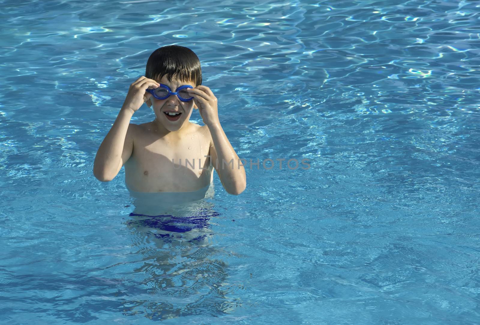 Child in swiming pool. Blue glasses