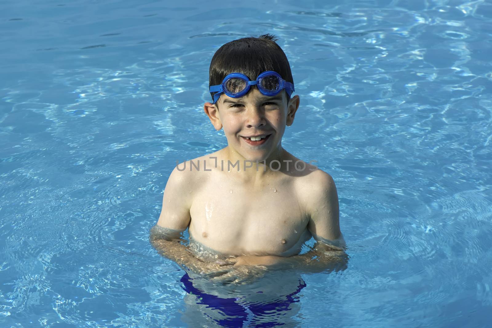 Child in swiming pool. Blue glasses