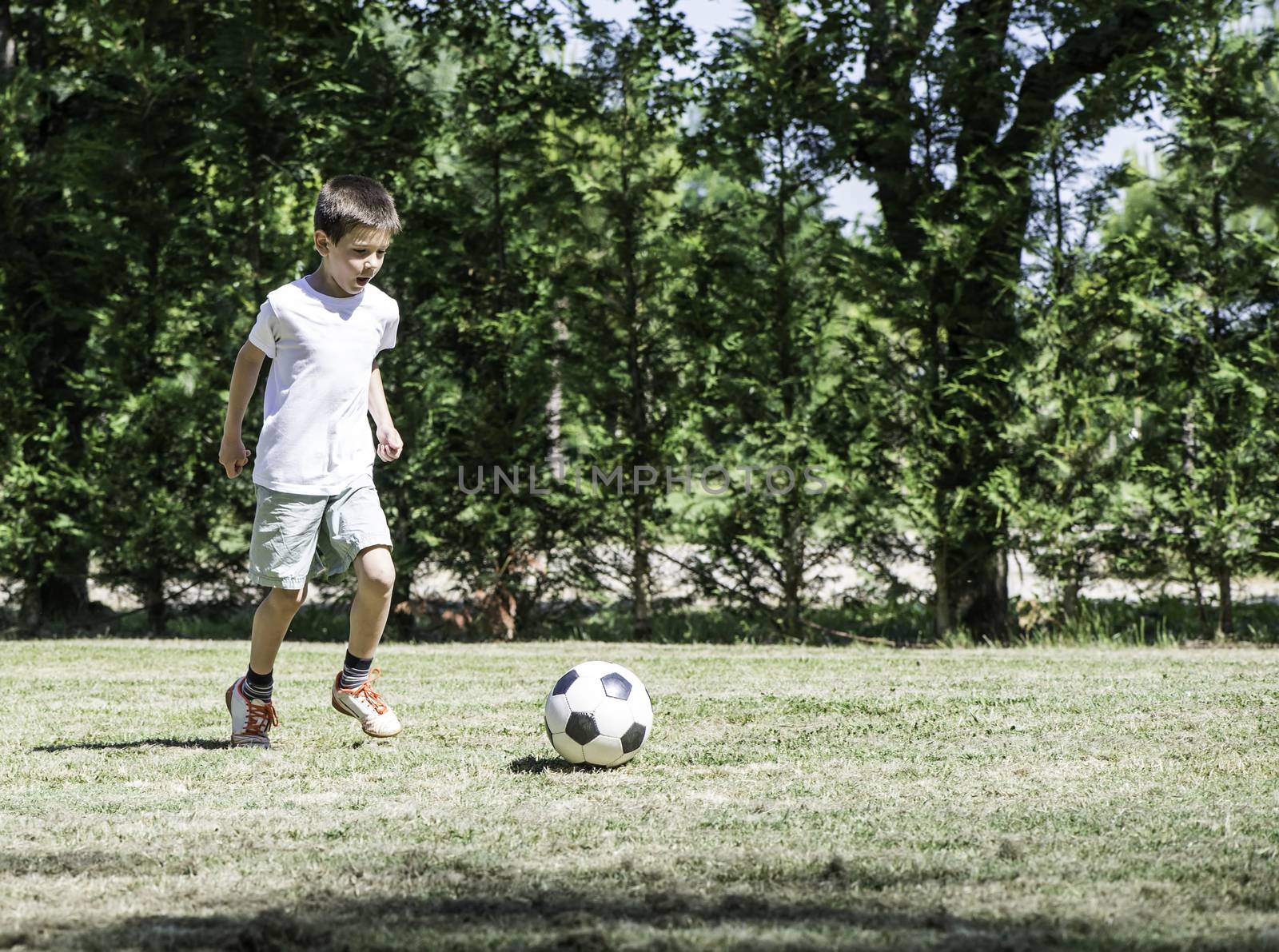 Child playing football in a stadium by deyan_georgiev