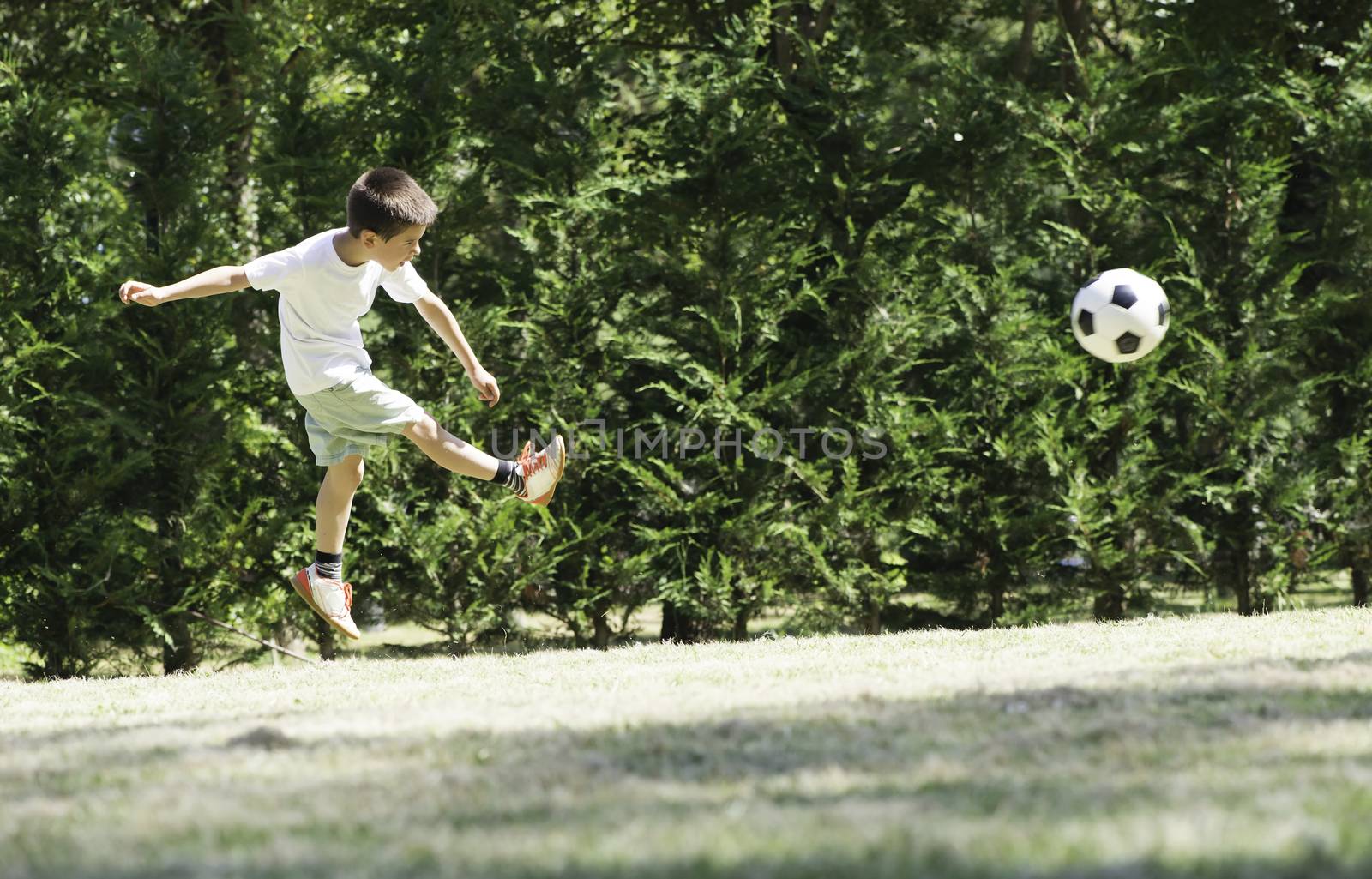 Child playing football in a stadium by deyan_georgiev