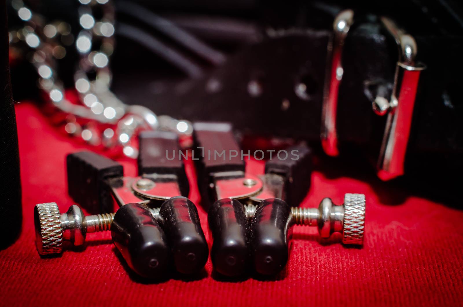 bdsm accessory human collar and accessory nipple clasp with metal chain on a red background close-up