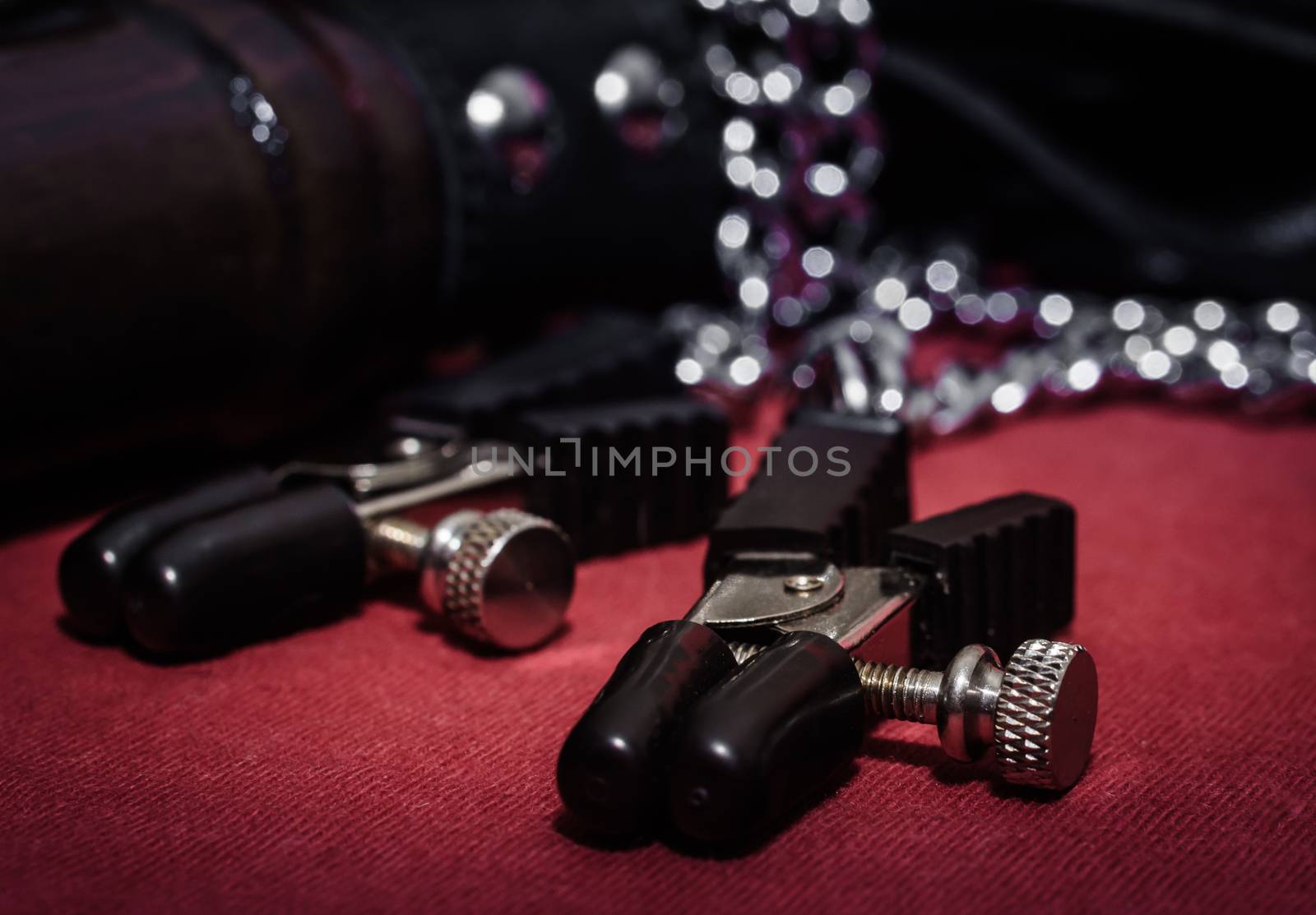 bdsm accessory nipple clasp with metal chain on a red background close-up