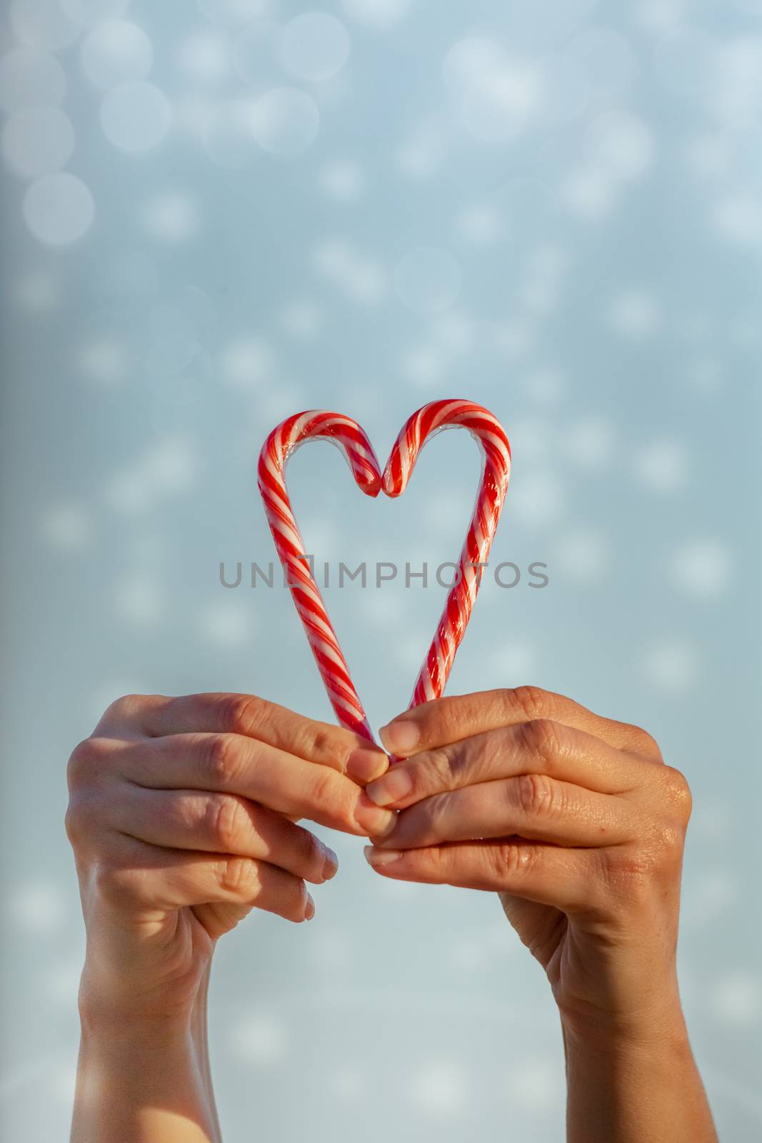 Love sweet wishes at Christmas.  A woman holds candy canes in the shape of a heart
