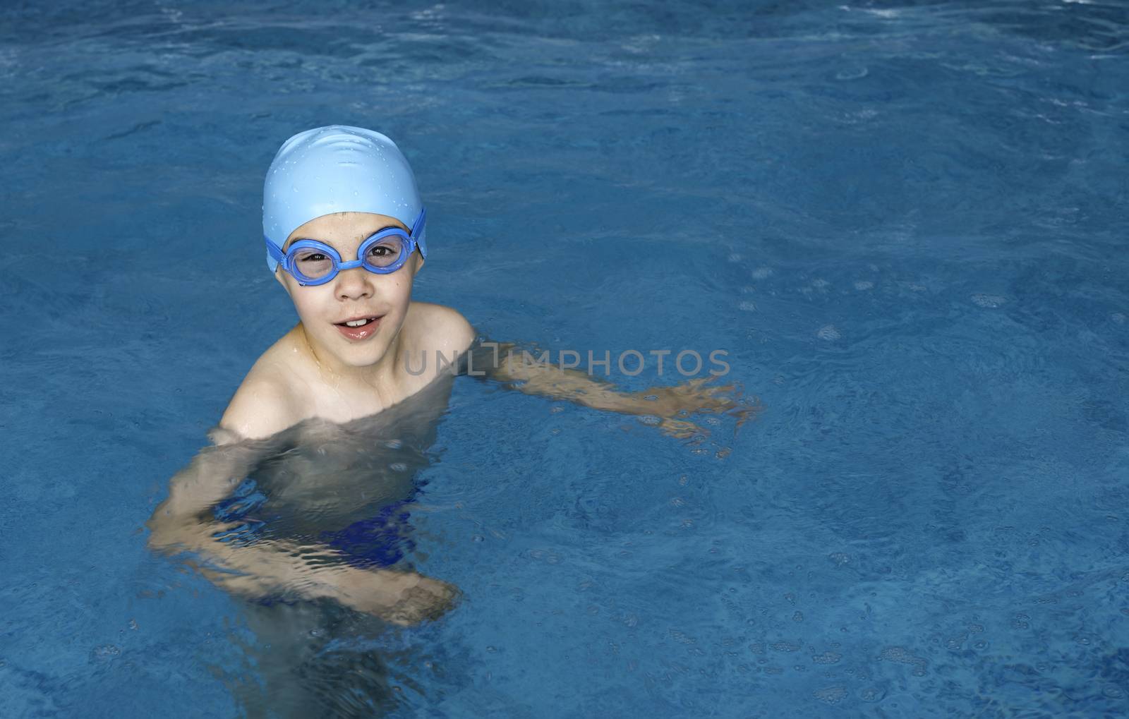 Little boy in swimming pool. Blue swimming pool.