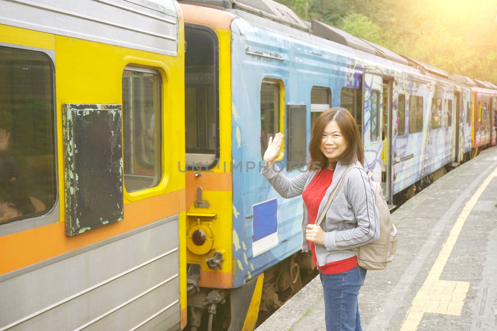 Asia backpacker woman feeling happiness and greeting his friend before getting on the train at the Pingxi Line historic train station in Taiwan . Travel and transportation concept.