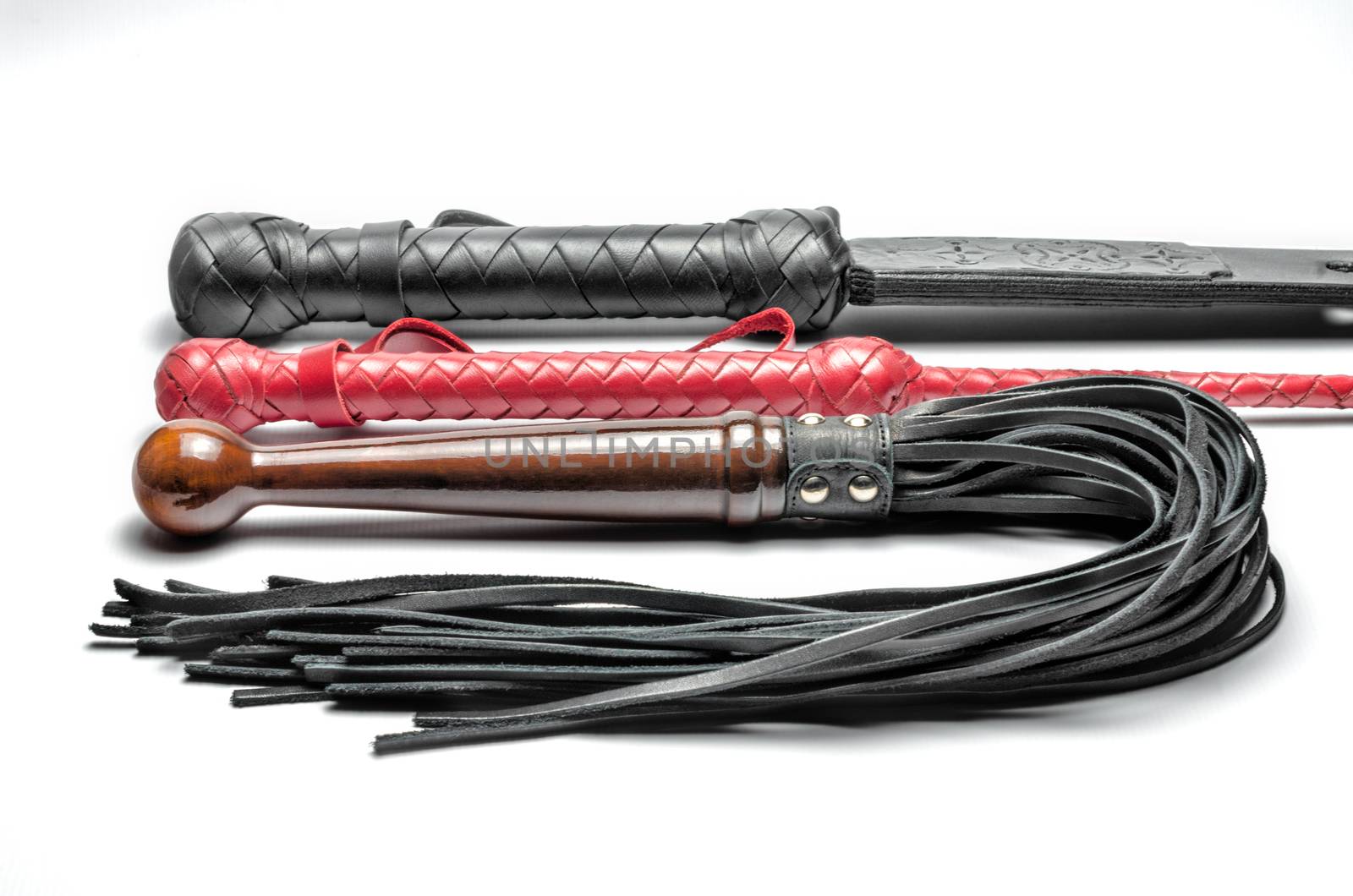 black and red three bdsm whips on a white background close up
