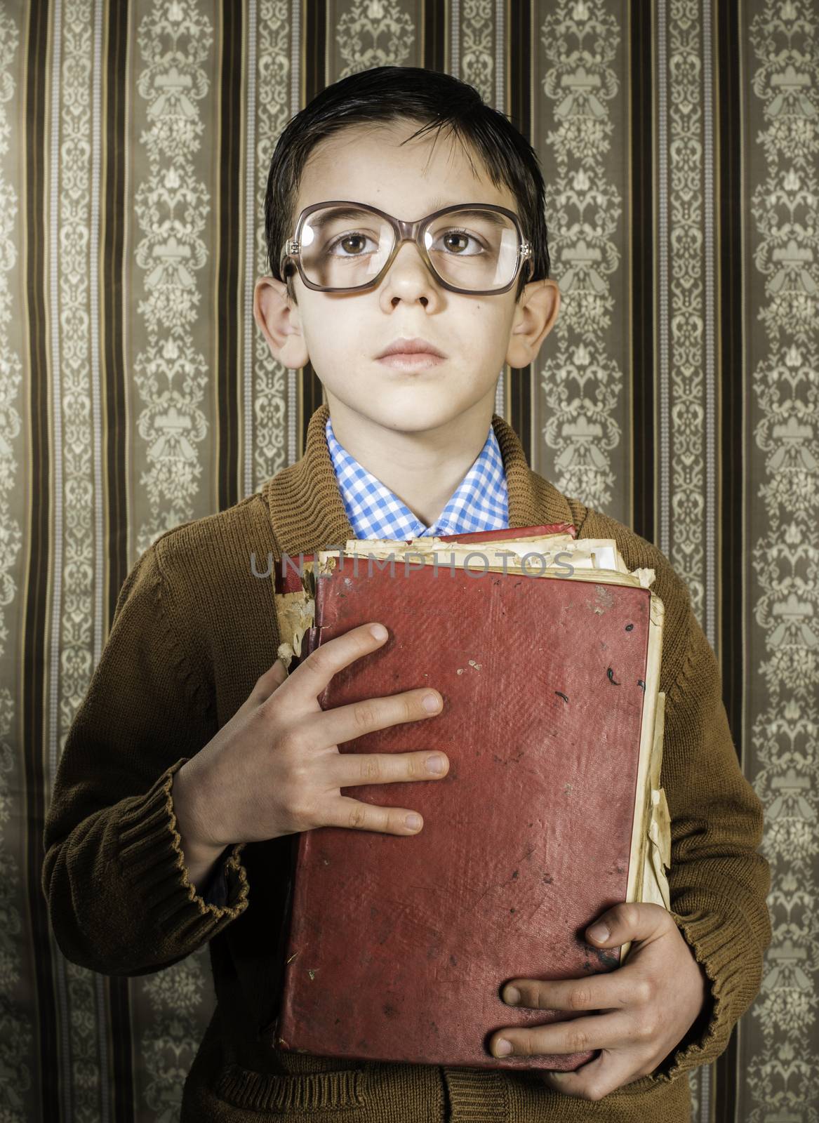 Child with glasses hold red vintage book. Vintage clothes