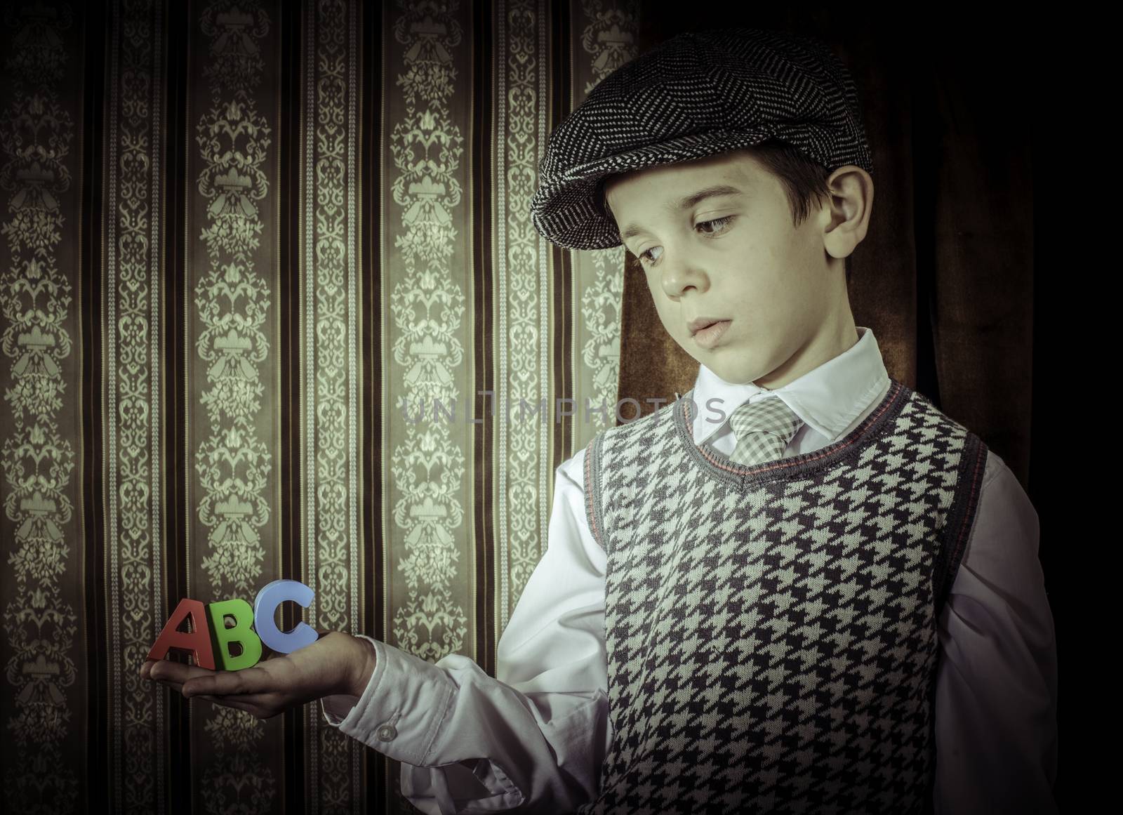Child in vintage clothes hold multicolor letters a b c