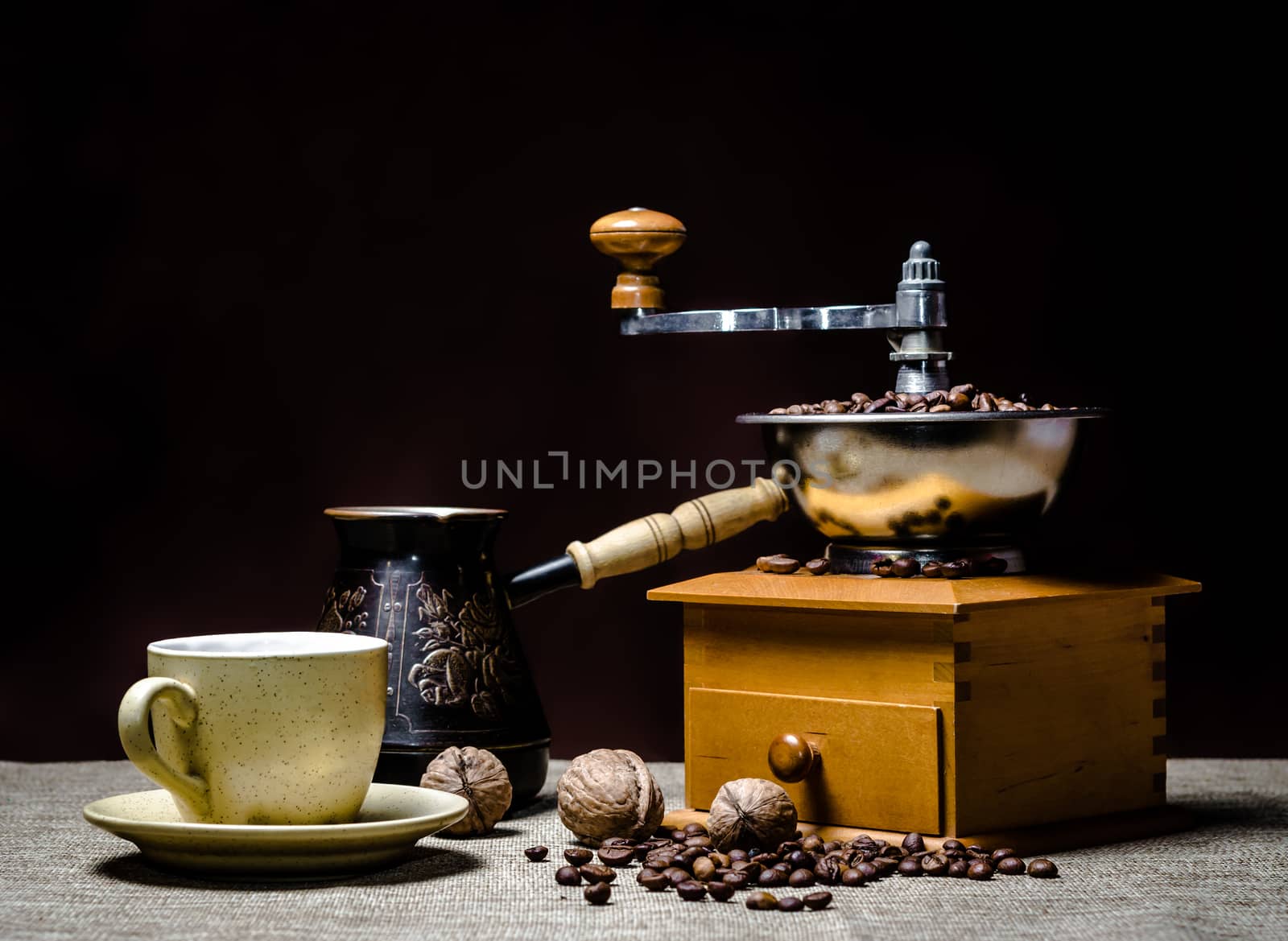coffee cup with a cezve and coffee grinder with coffee beans and nuts on a dark background