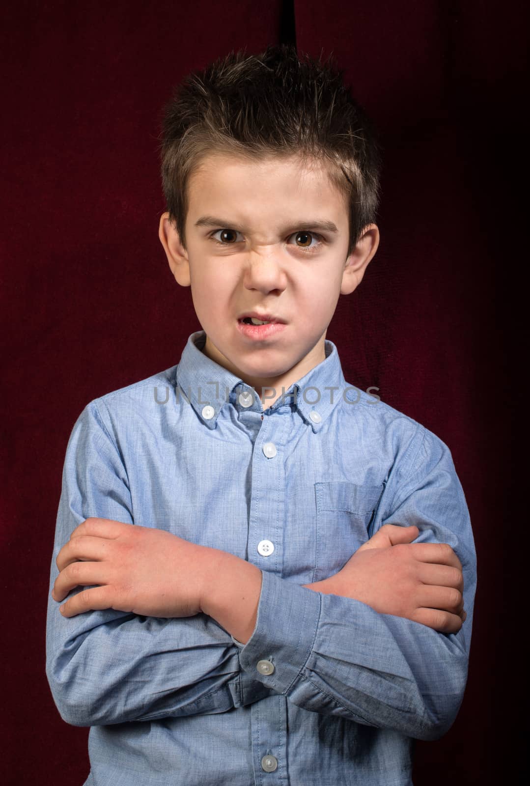 Frowning boy in blue shirt on red background