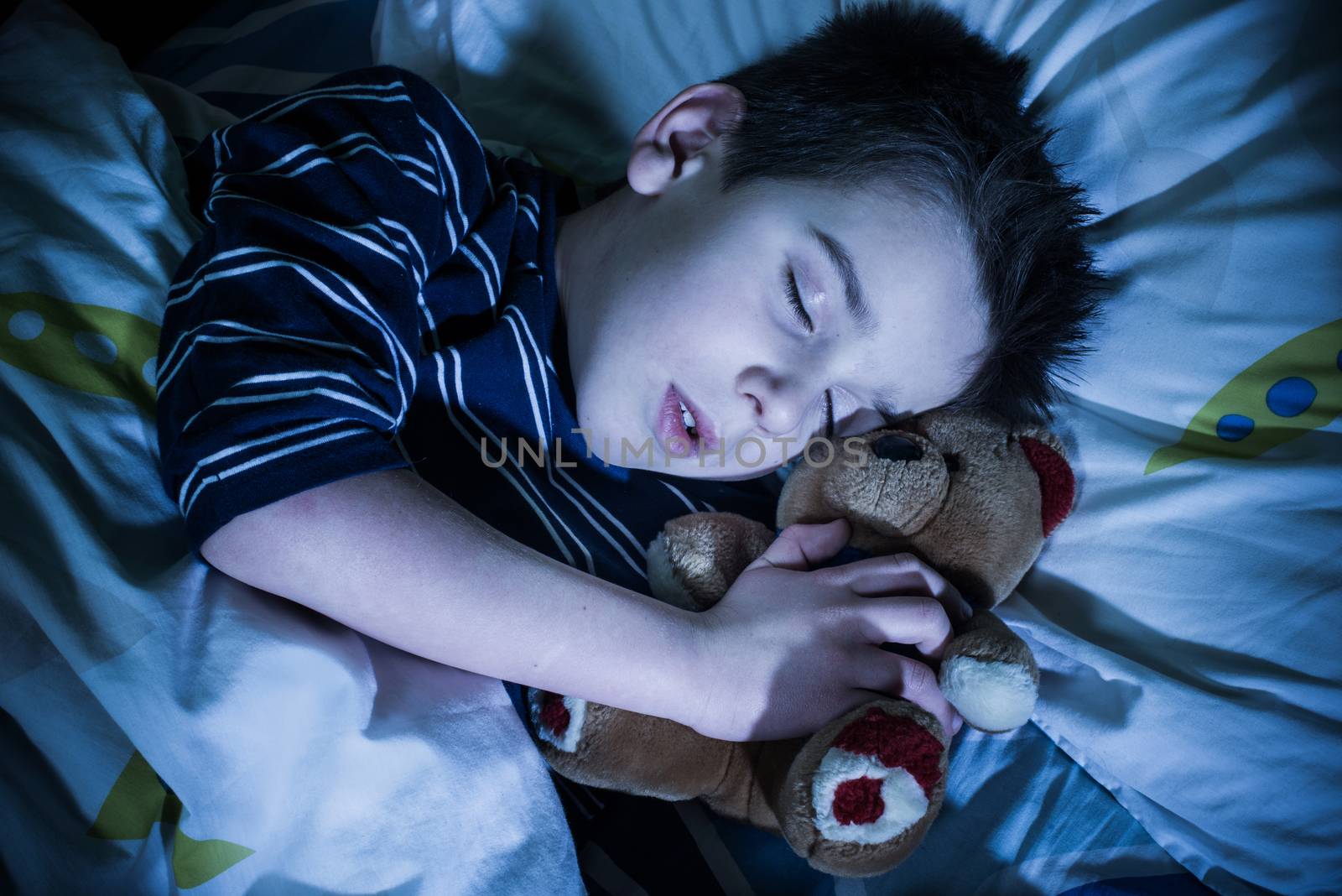 Sleeping child with his toy bear.